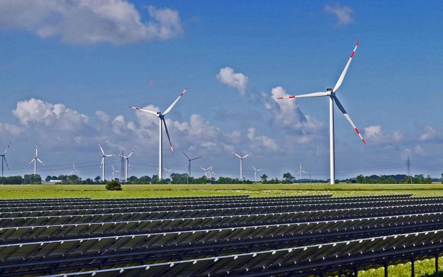 Ein Energiepark mit einer Freiflächen-Photovoltaikanlage im Vordergrund und Windkraftanlagen im Hintergrund