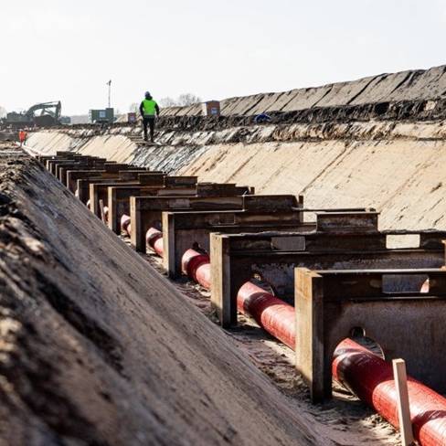 In einem tiefen, breiten Graben verläuft ein Höchstspannungs-Erdkabel diagonal durchs Bild