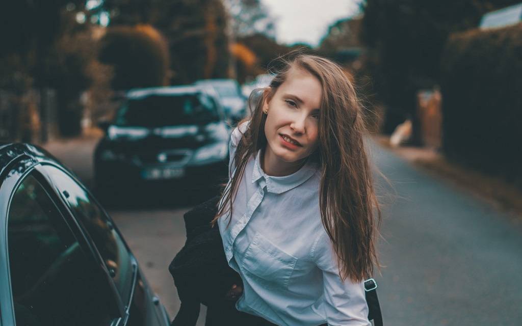 Junge Frau im Business-Dress neben einem Auto