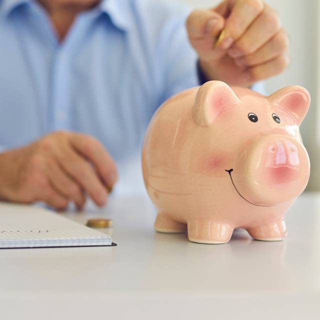 Ein Mann steckt Geld in ein Sparschwein.