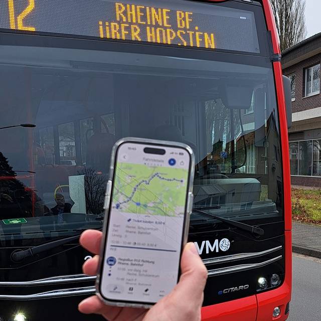 Im Hintergrund ein RVM-Bus, im Vordergrund eine Hand, die ein Handy hält. Darauf zu sehen: Die neue Busverbindung in der App.