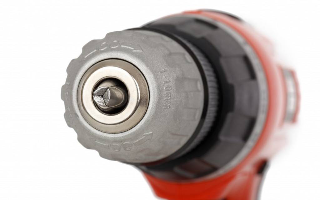 Detailansicht einer roten Bohrmaschine von vorne mit blick auf das Bohrfutter. Alles andere ist unscharf.