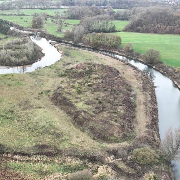 Drohnenaufnahme eines Emsabschnitts. Die Ems mäandert in diesem Bereich stark. Teilweise sind Uferböschungen zu erkennen, teilweise kleine Sandstrände. Zwischen den Emsschleifen unberührte Natur, weiter außen die typische münsterländische Parklandschaft mit Feldern, Wallhecken und Waldstücken.