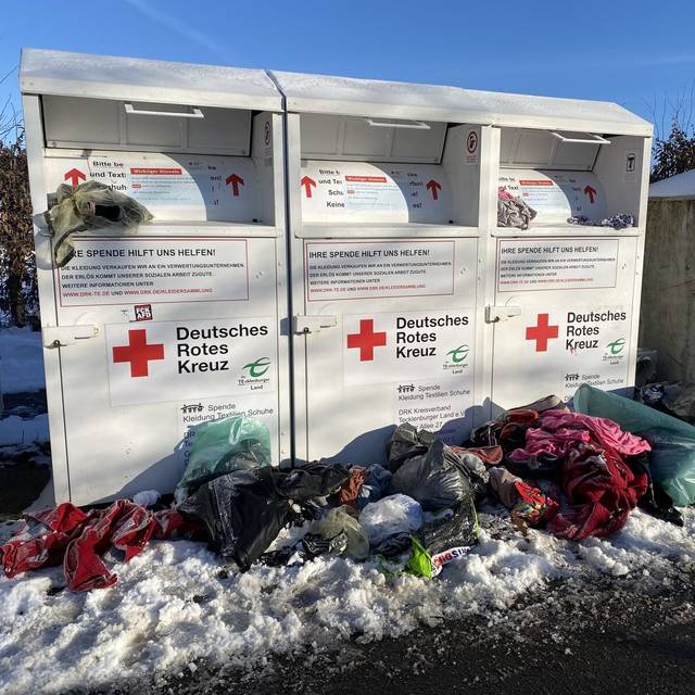Vor den Altkleider-Containern des DRK liegen viele Säcke mit Müll.