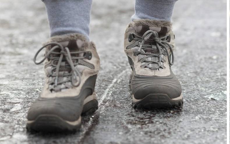 Jemand läuft über einen vereisten Gehweg.