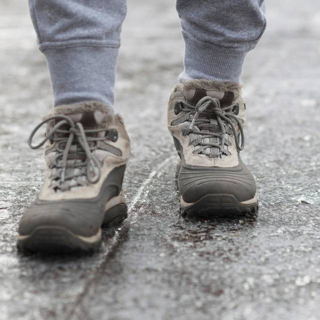 Jemand läuft über einen vereisten Gehweg.