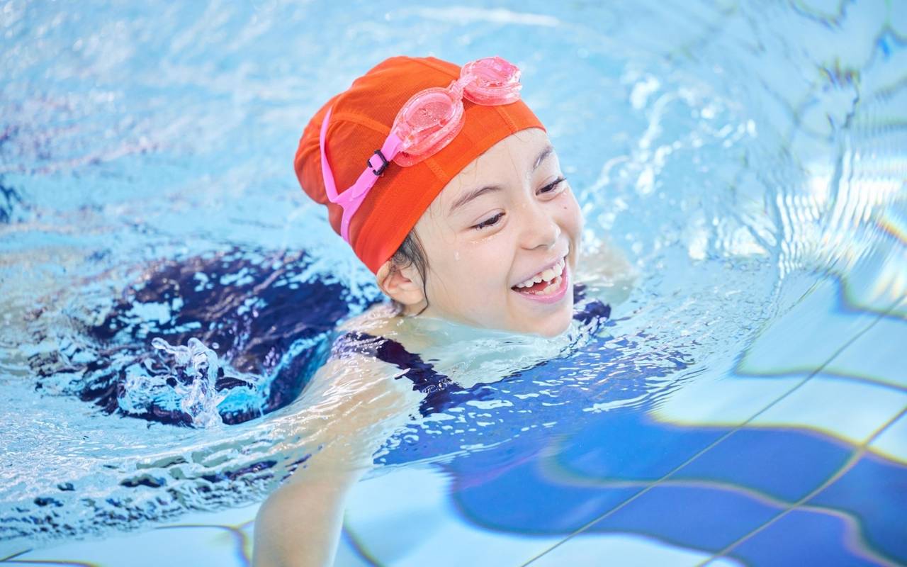 Ein Mädchen schwimmt in einem Schwimmbad.