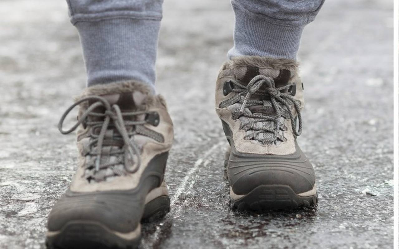 Jemand läuft über einen vereisten Gehweg.