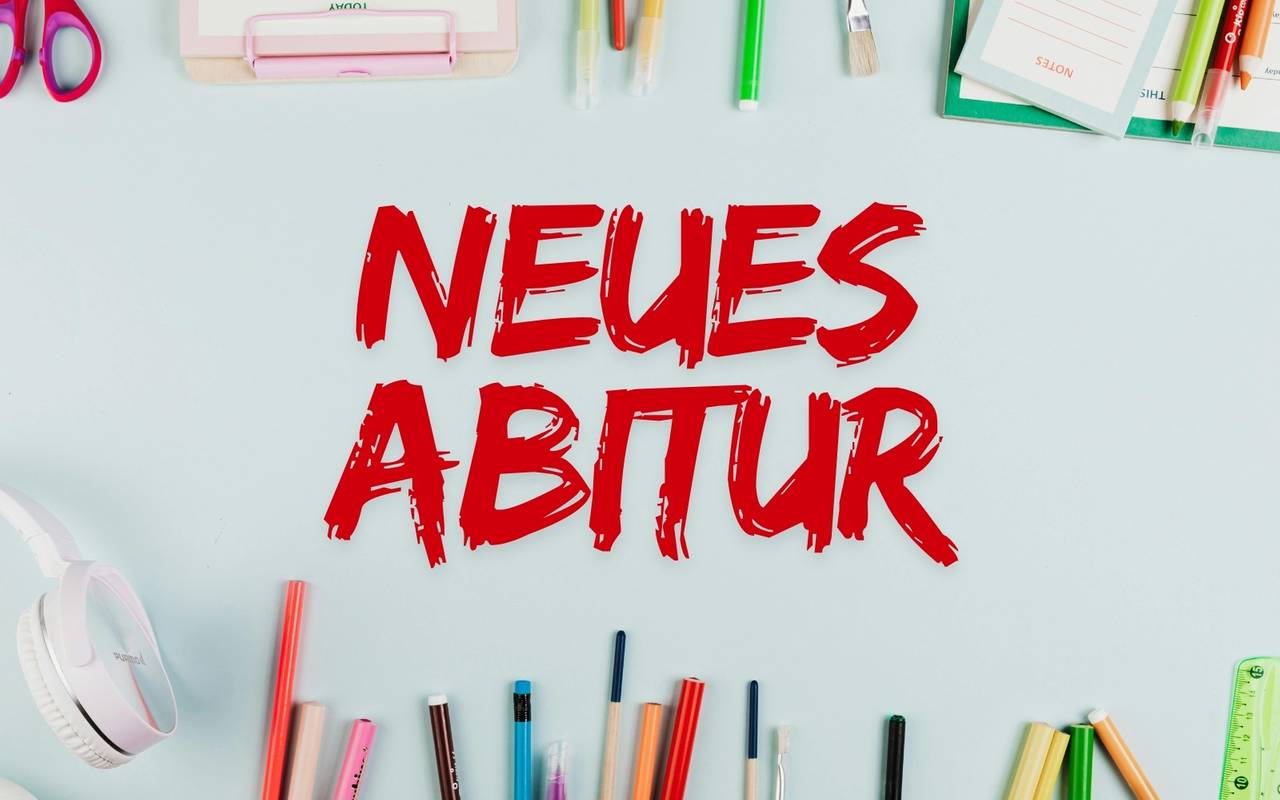 Stifte und andere Schulmaterialien liegen auf einem Tisch. Auf dem Tisch steht: "Neues Abitur"
