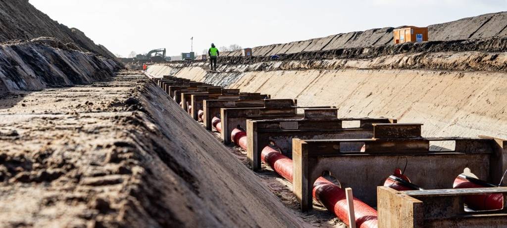 In einem tiefen, breiten Graben verläuft ein Höchstspannungs-Erdkabel diagonal durchs Bild