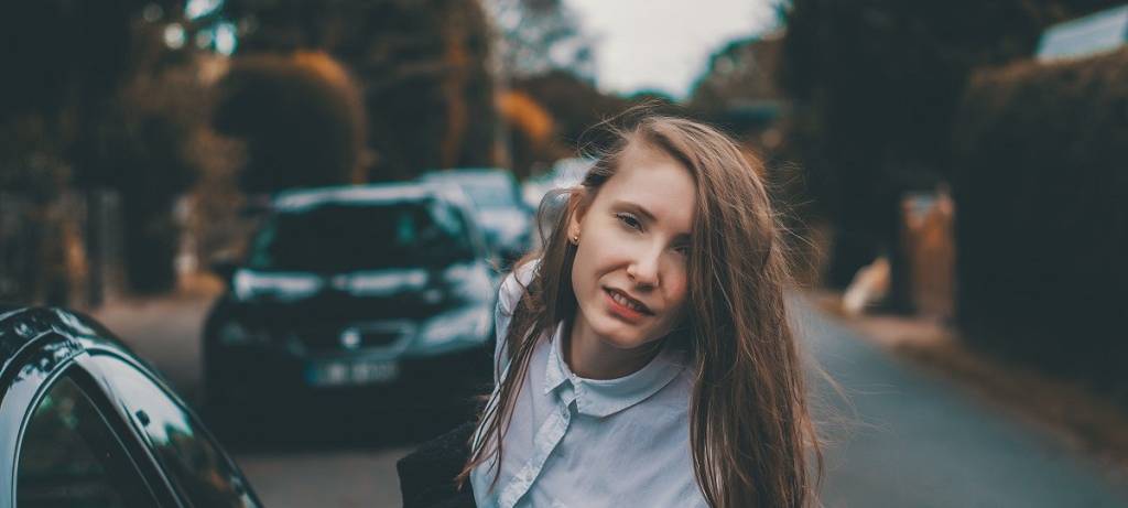 Junge Frau im Business-Dress neben einem Auto