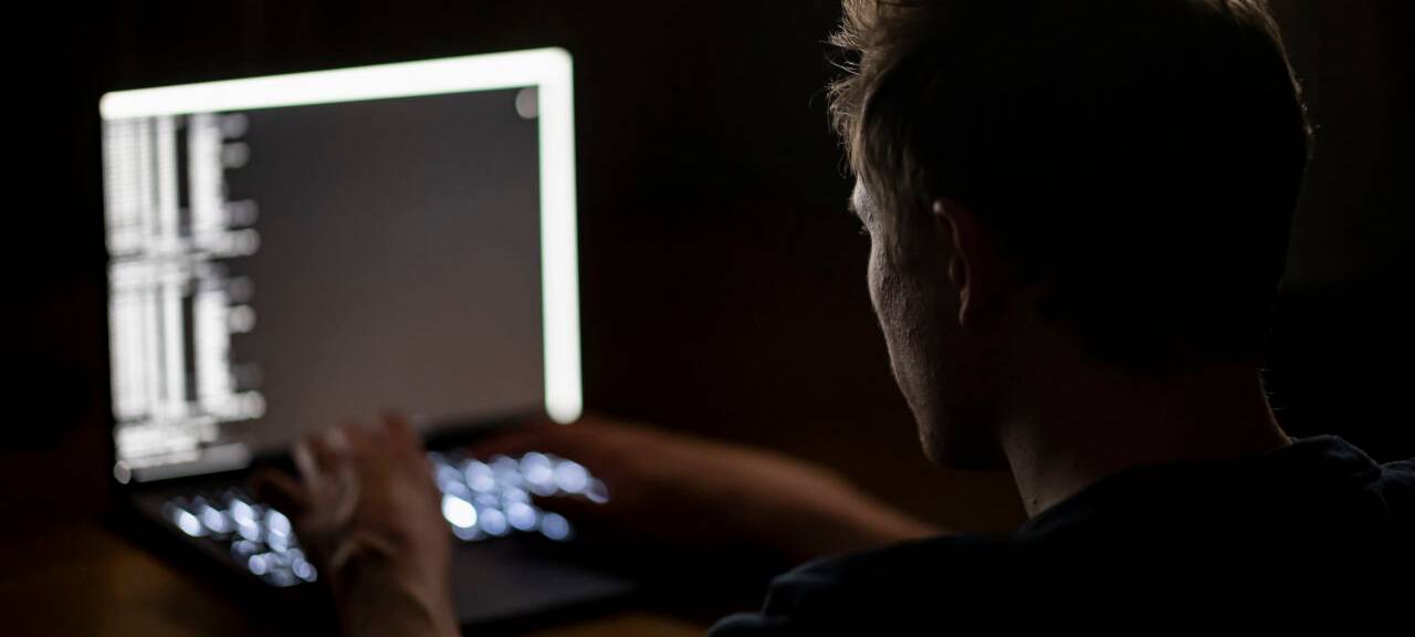 Ein Mann schreibt auf der Tastatur eines Laptops.