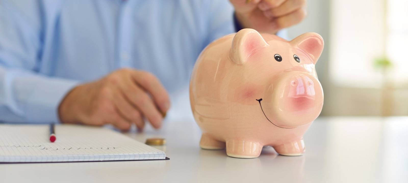 Ein Mann steckt Geld in ein Sparschwein.