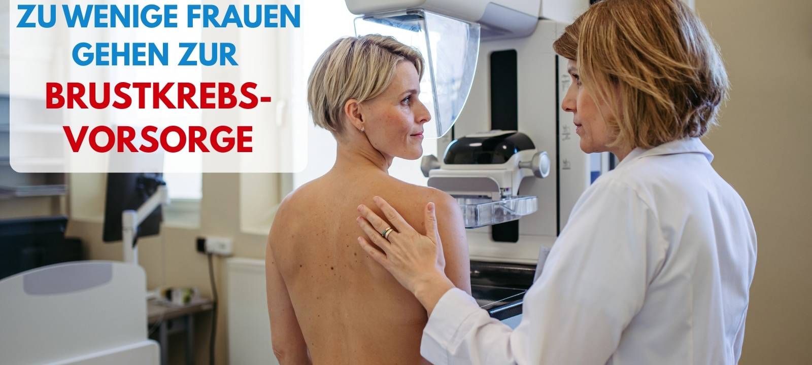 Eine Ärztin und eine Frau stehen nebeneinander. Die Frau steht vor einer Maschine zur Brustkrebsvorsorge.