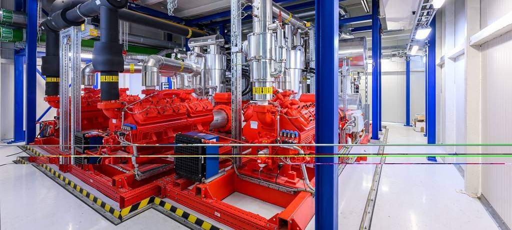 Aufnahme einer Großwärmepumpe: Eine überwiegend rote Anlage in einer Halle mit einer brauen Tragkonstruktion aus Stahlträgern.
