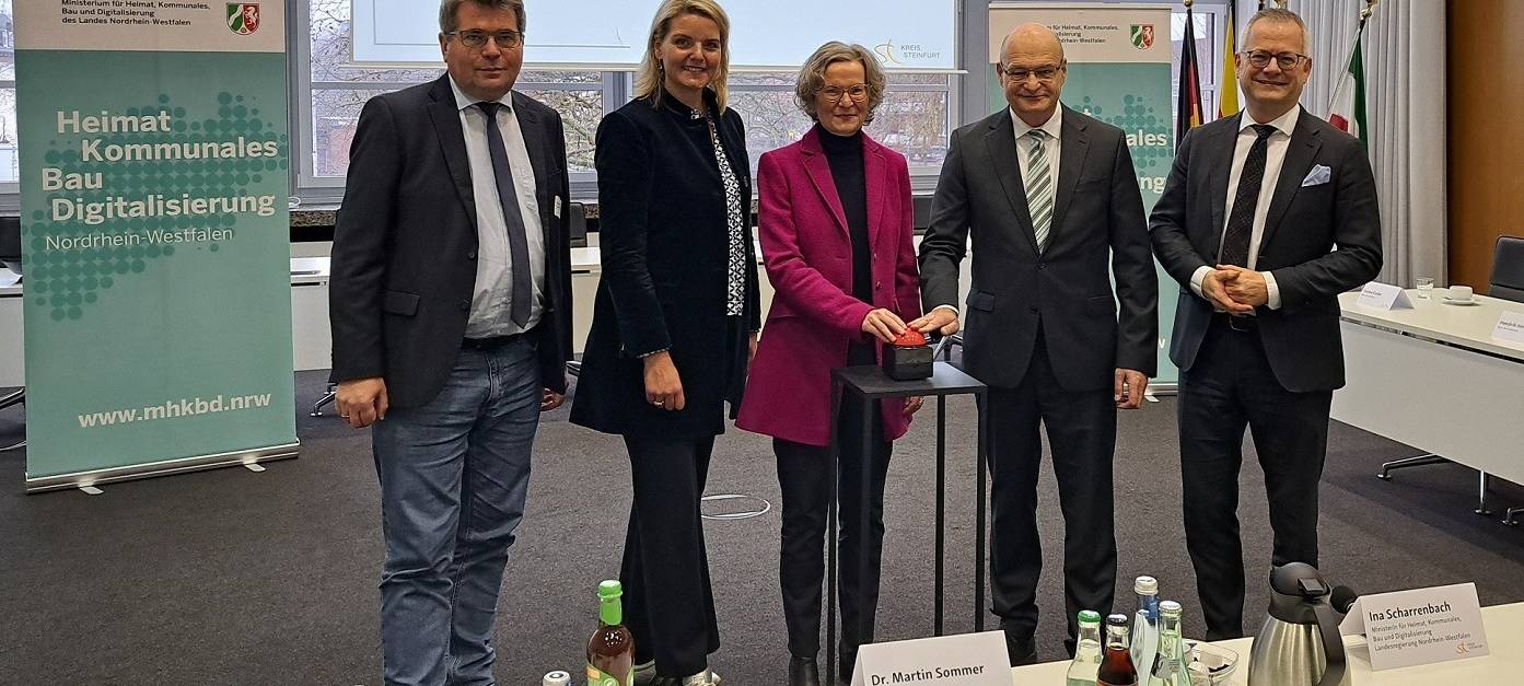 Start des neuen Bauportals mit NRW-Bauministerin Ina Scharrenbach. Ministerin und Landrat drücken Start-Button. Im Hintergrund eine Präsentation auf der Leinwand und ein Banner des Bauministeriums
