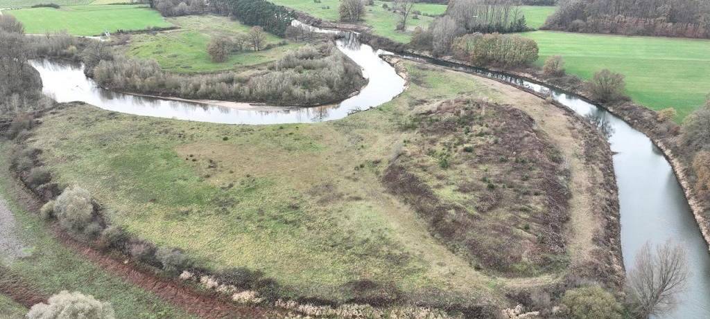 Drohnenaufnahme eines Emsabschnitts. Die Ems mäandert in diesem Bereich stark. Teilweise sind Uferböschungen zu erkennen, teilweise kleine Sandstrände. Zwischen den Emsschleifen unberührte Natur, weiter außen die typische münsterländische Parklandschaft mit Feldern, Wallhecken und Waldstücken.