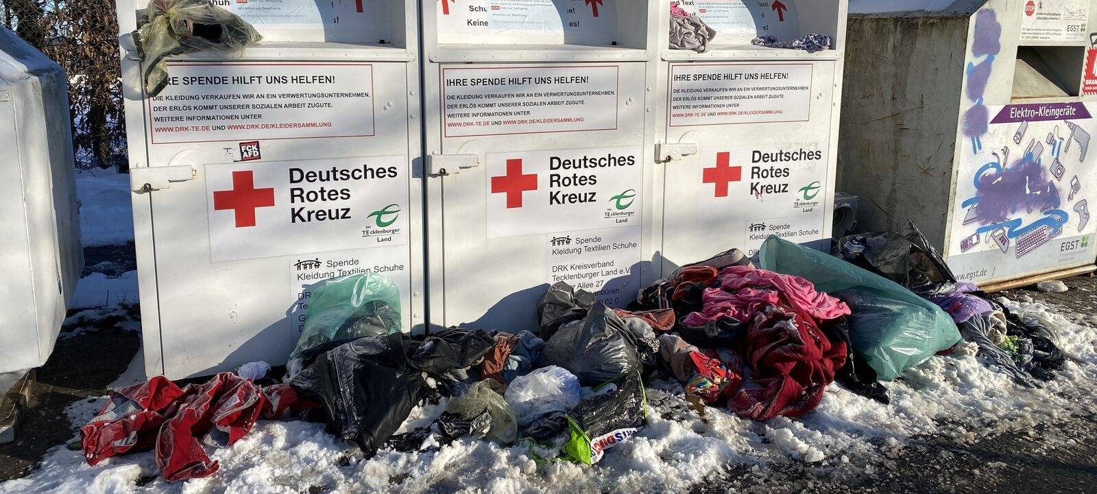 Vor den Altkleider-Containern des DRK liegen viele Säcke mit Müll.