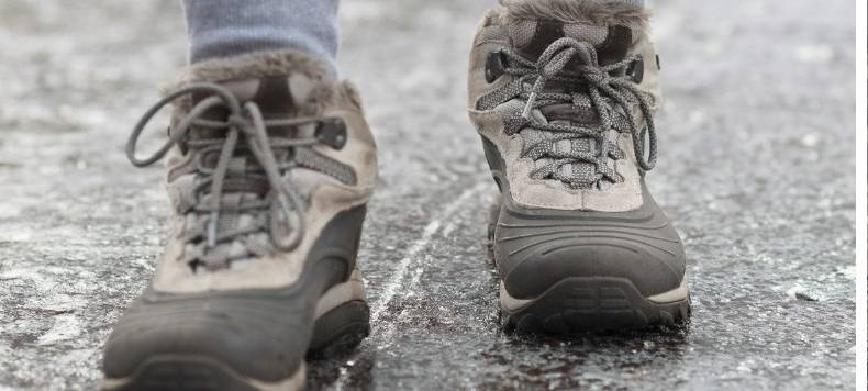 Jemand läuft über einen vereisten Gehweg.