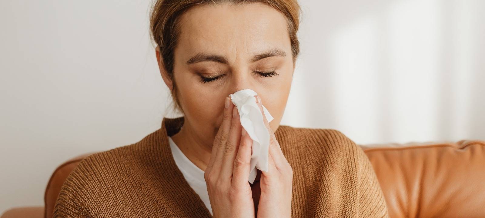 Eine Frau putzt sich die Nase.