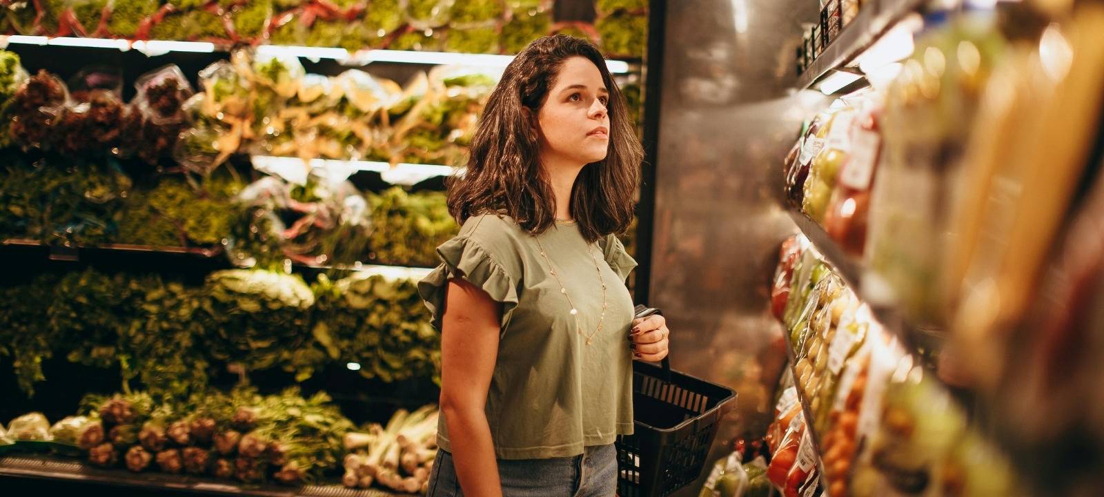 Eine Frau steht im Supermarkt und schaut in ein Regal.