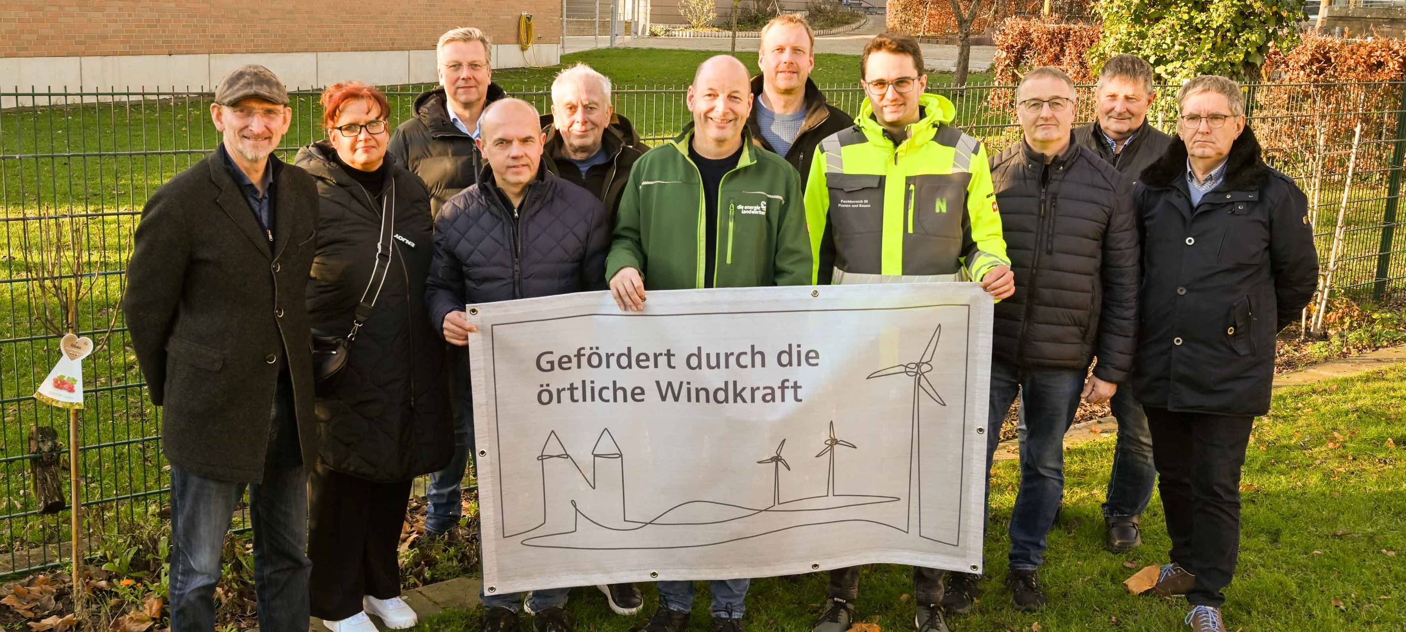Vertretende von Windenergieanlagen rund um Neuenkirchen posieren für ein Gruppenbild.