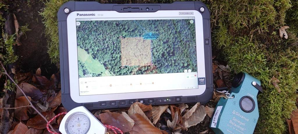 Drei Spezialgeräte für Waldinventur auf Waldboden mit Laub und Moos