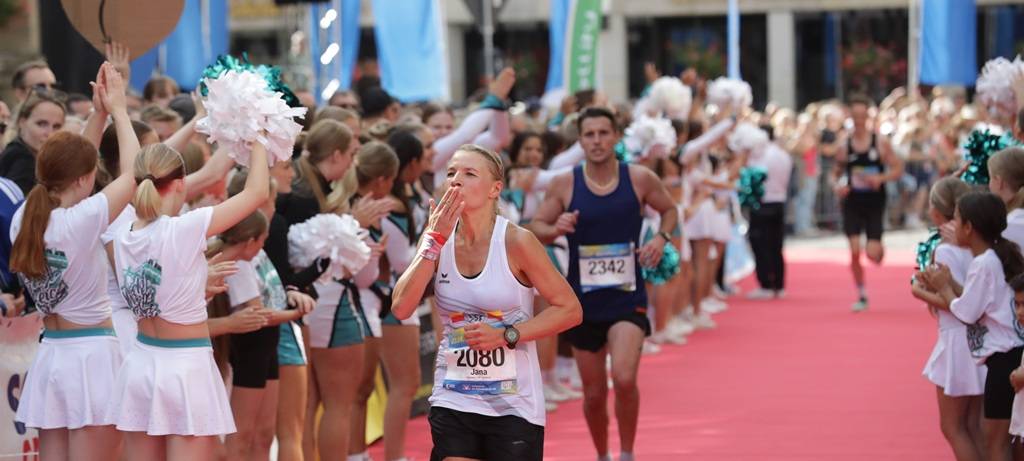 Marathonläuferin Jana Kappenberg aujs Münster beim Zieleinlauf auf rotem Teppich mit Kusshändchen.