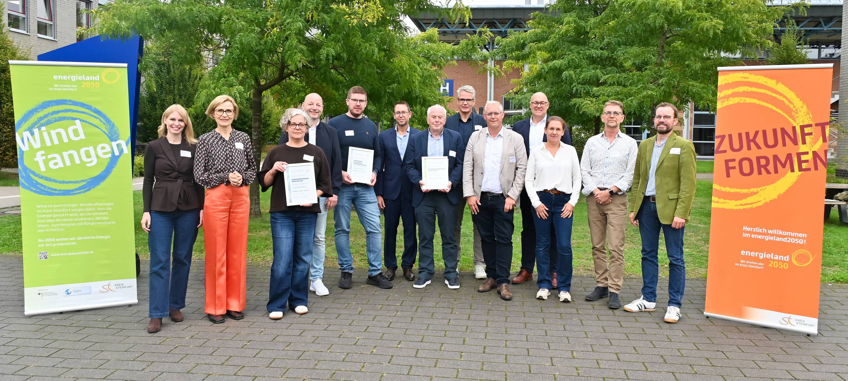 Vertreter von Bürgerwindparks stehen für ein Gruppenfoto zusammen.
