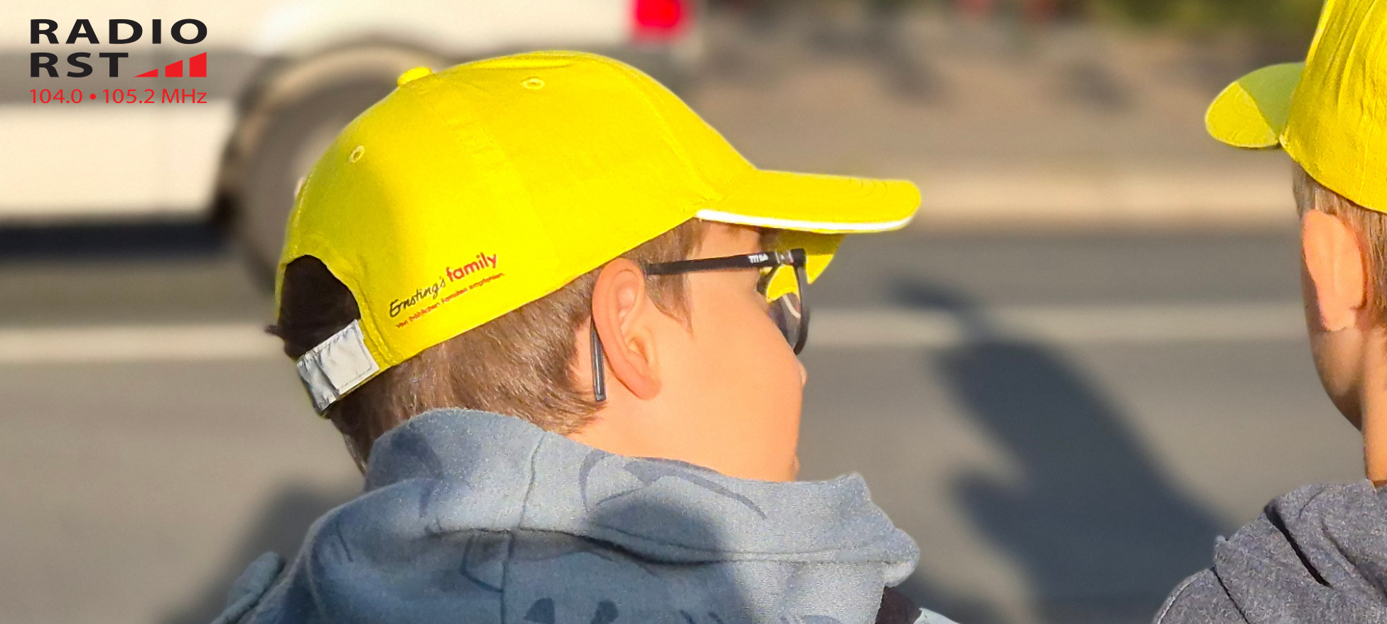 Ein Kind trägt eine gelbe Cappy und schaut auf die Straße.